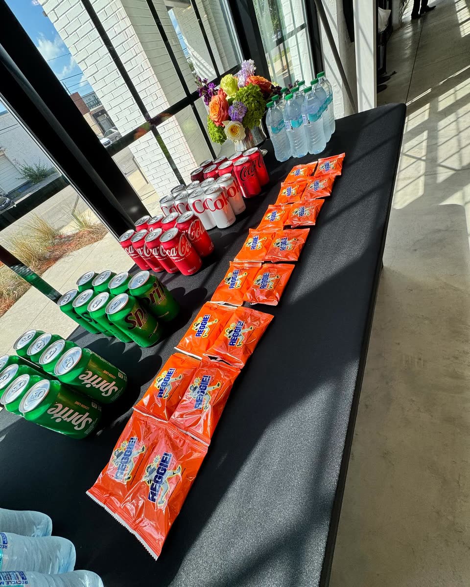 Dozens of REGGIE! Bars laid out in long rows on an event table beside cans of soda